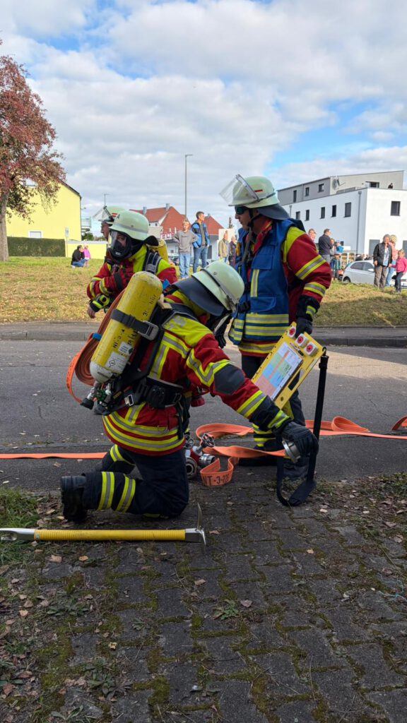 Der Angriffstrupp schließt das erste Rohr am Verteiler an. Der Gruppenführer nimmt den Druck in der Atemschutzflasche auf.