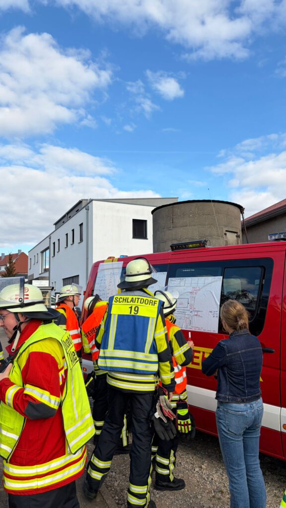 Das MTW der FF Schlaitdorf fungierte als Einsatzleitwagen. An diesem Besprechen die Führungskräfte die aktuelle Lage und das weitere Vorgehen.
Auf dem Bild sind mehrere Personen vor einem Fahrzeug mit Karten zu sehen.