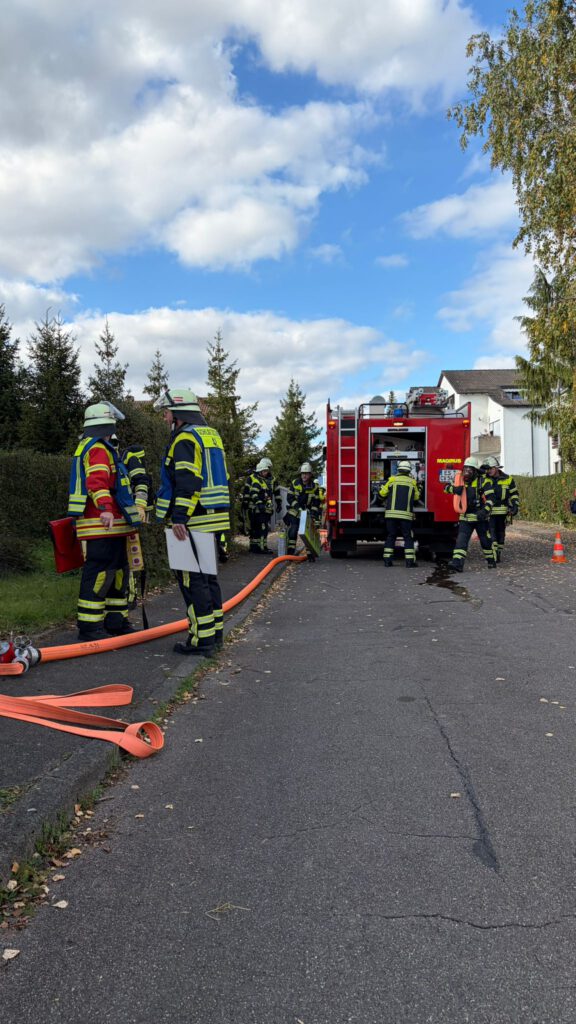 Lagebesprechung der Gruppenführer der ersten beiden Fahrzeuge. Am Fahrzeug sind die Trupps bei der Ausrüstung zu sehen.
Auf dem Bild sind zwei Gruppenführer bei der Besprechung zu sehen. Im Hintergrund sieht man wie die Trupps der FF Schlaitdorf sich am Löschgruppenfahrzeug ausrüsten.